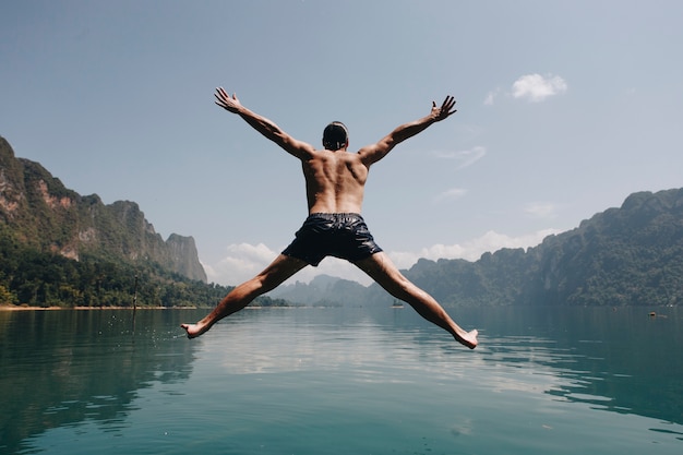 Homem pulando de alegria por um lago