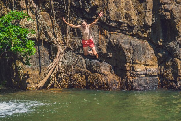 Homem pulando do penhasco na água. estilo de vida divertido de verão.