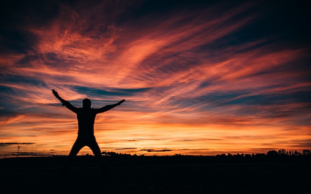 Homem pulando no pôr do sol