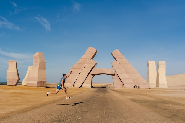 Homem pulando perto do enorme portão do parque nacional de Allah Ras Mohammed no deserto do Egito