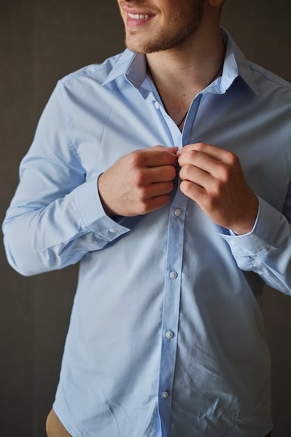 Foto homem que ajusta seus botões de camisa.