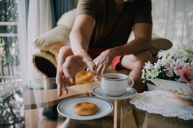 Homem que alcança para agarrar cookies e café.