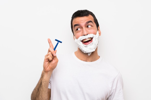 Homem que barbeia sua barba sobre o fundo branco isolado que pretende realizar a solução ao levantar um dedo acima