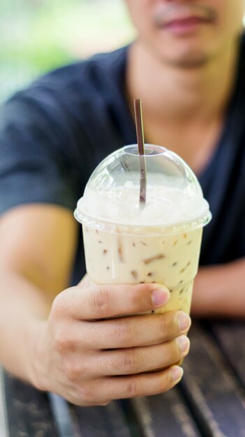 Homem que bebe um café congelado em uma cafetaria.