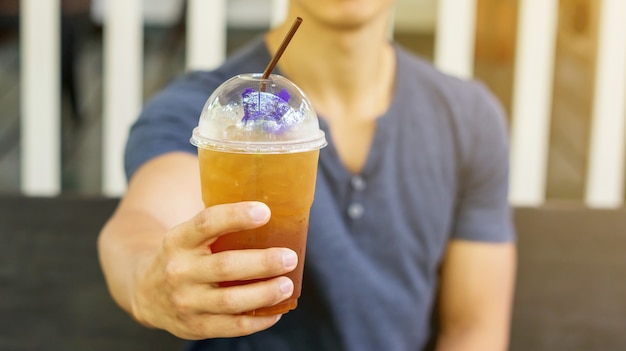 Homem que bebe um chá congelado da fruta em um café.