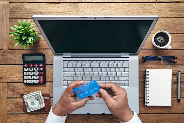 Homem que guarda o cartão de crédito e que usa o laptop.