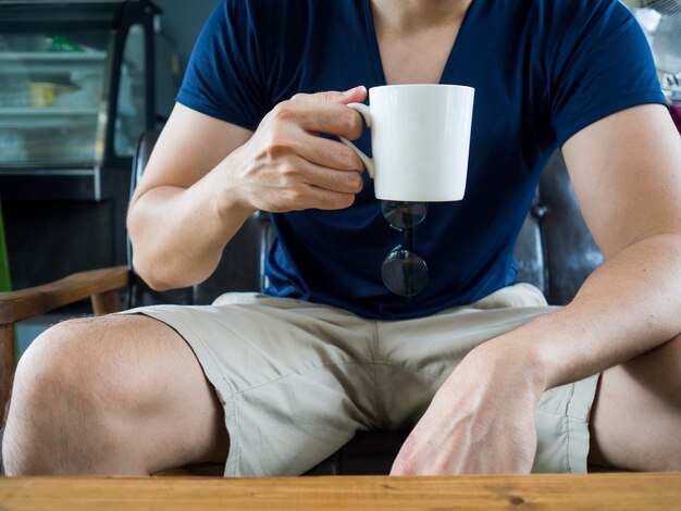 Homem que guarda uma caneca branca de bebida quente.