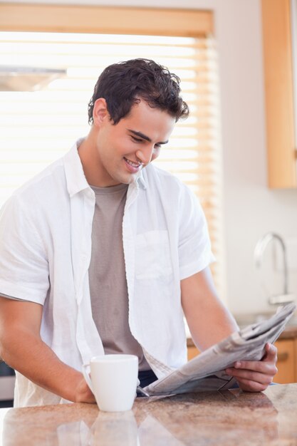 Homem que lê jornal na cozinha