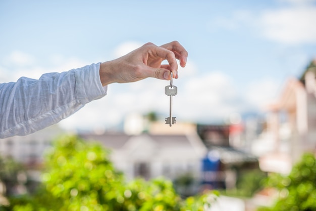 Homem que mantém a chave da casa no fundo das casas da cidade. lidar com o conceito imobiliário