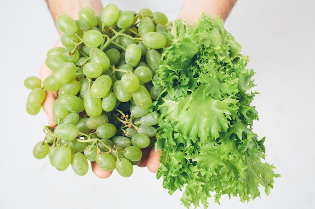 Homem que mantém saladas e uva, fim. conceito. isolado no branco