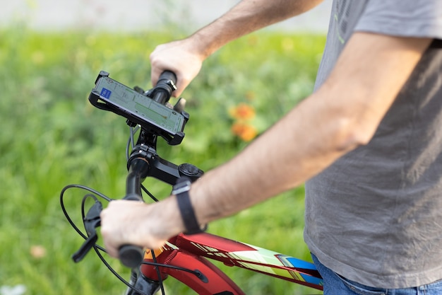 Homem que planeja a rota usando o aplicativo de navegação GPS no celular em sua bicicleta.