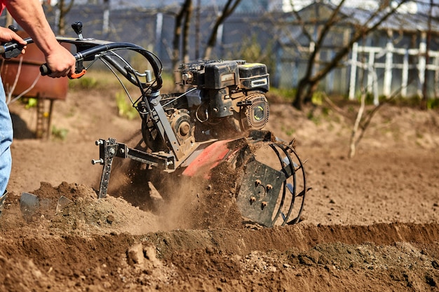 Homem que trabalha no jardim com rebento de jardim. Rebento de jardim para trabalhar, close-up. Homem com trator, cultivando o campo na primavera.