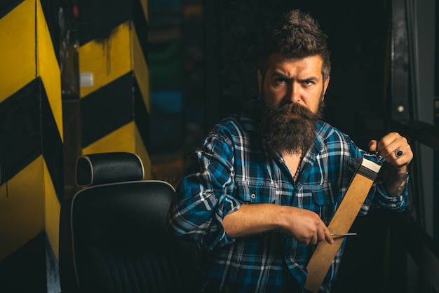 Homem que visita o cabeleireiro na barbearia. Trims. Barbeiro fazendo a barba de um homem barbudo em uma barbearia. Ele é