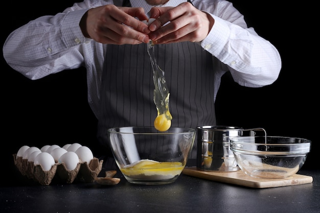 Homem quebrando ovo em uma tigela cozinhando massa