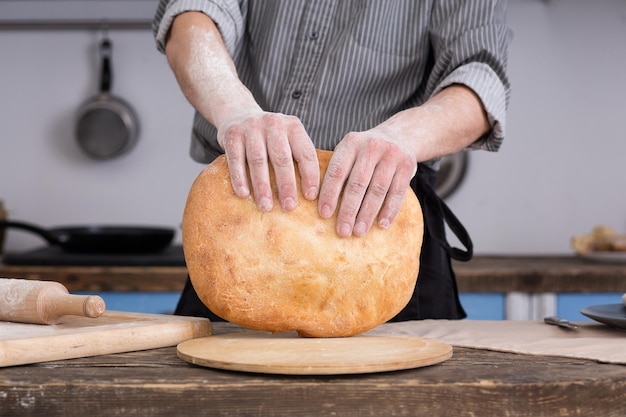 Homem rasgando pão pita na cozinha