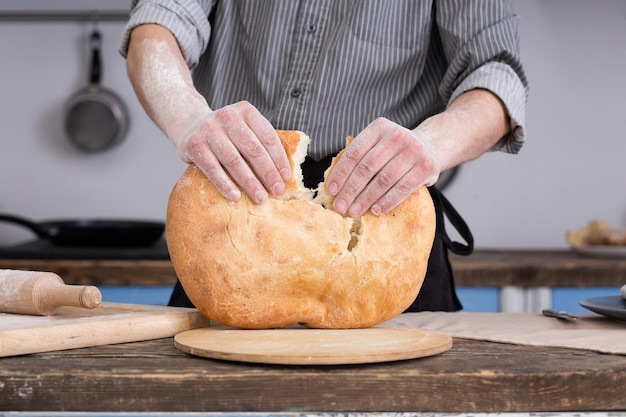 Homem rasgando pão pita na cozinha