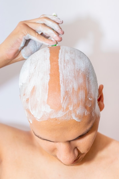 Homem raspando a cabeça usando espuma branca