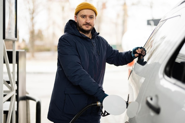 Homem reabastecendo seu carro suv americano no posto de gasolina em tempo frio