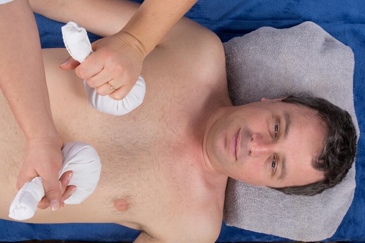 Foto homem recebendo massagem com bola de ervas no belo spa.