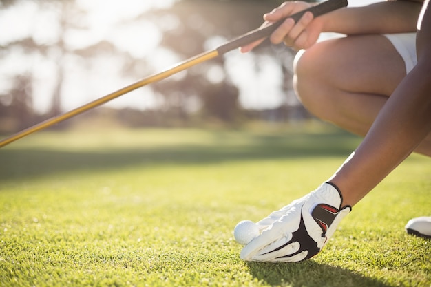 Homem recortado golfista colocando bola de golfe no tee