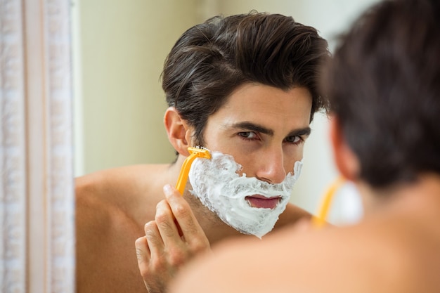 Homem refletindo no espelho enquanto raspar a barba