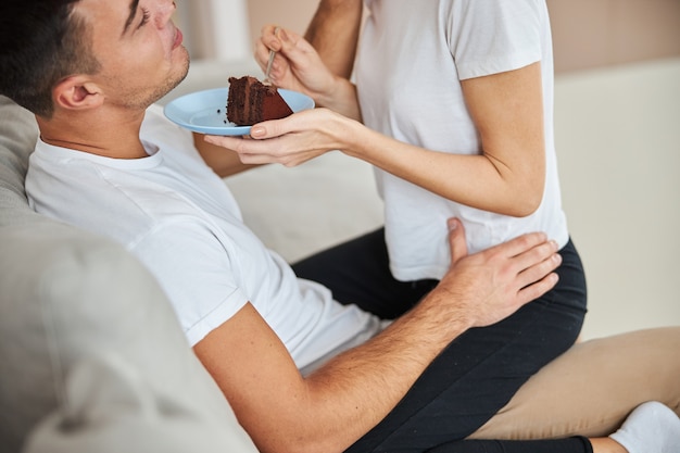 Homem relaxado comendo bolo de chocolate com sua namorada