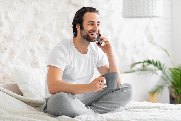 Homem relaxado tendo telefonema enquanto bebe café