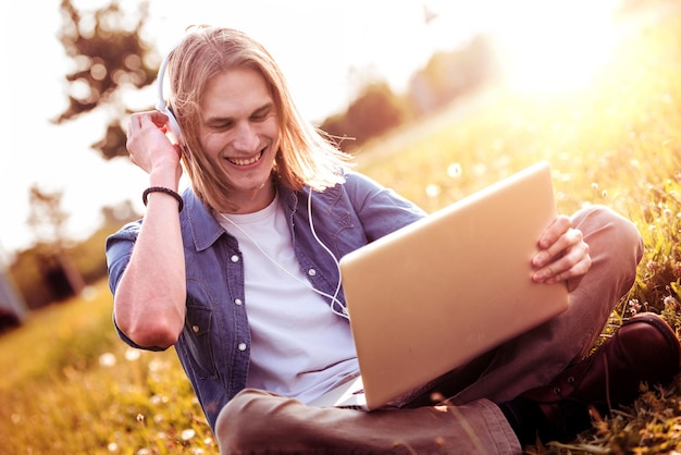 Homem relaxando ao ar livre com seu laptop