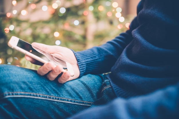 Homem relaxando em casa com smartphone na mão