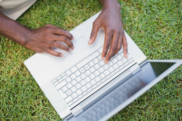 Homem relaxando em seu jardim usando laptop