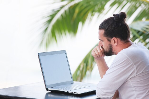 Homem relaxando na praia com o trabalho dos sonhos de freelancer laptop no local de trabalho