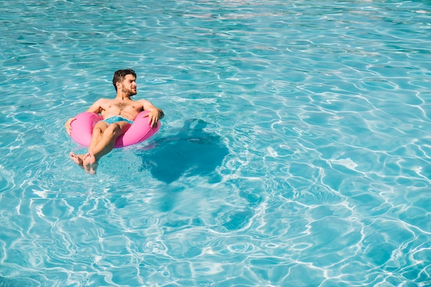 Foto homem relaxando no anel inflável na piscina