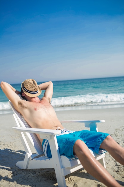 Homem relaxante na espreguiçadeira na praia