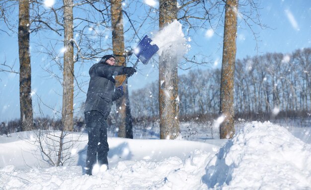 Homem remove neve com uma pá da estrada no inverno nevado