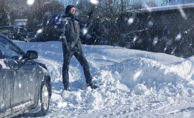 Homem remove neve com uma pá da estrada no inverno nevado