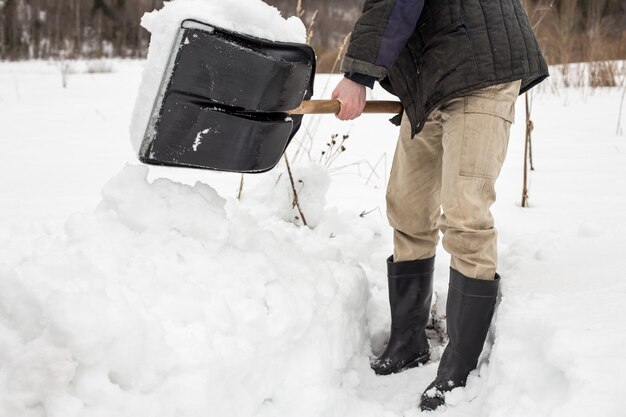 Homem remove neve da trilha usando uma pá no inverno na aldeia