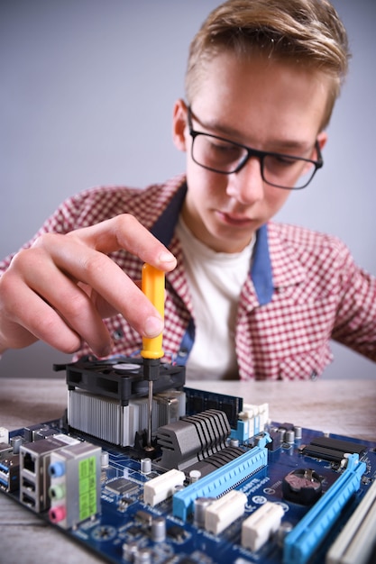 Homem reparando computador quebrado, placa de vídeo, memória RAM, refrigerador, processador, disco rígido. Jovem reparador trabalhando com chave de fenda no centro de serviço.