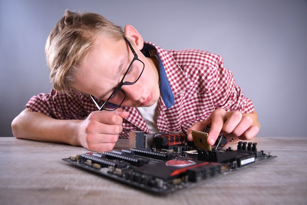 Homem reparando computador quebrado, placa de vídeo, memória ram, refrigerador, processador, disco rígido. jovem reparador trabalhando com chave de fenda no centro de serviço.