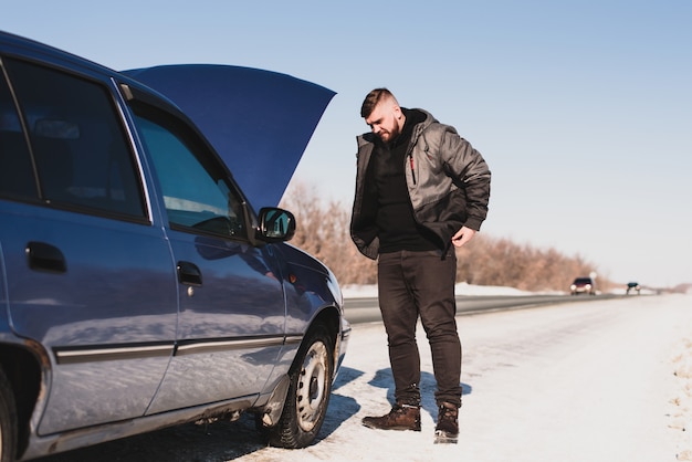 Homem reparando um carro parado no capô