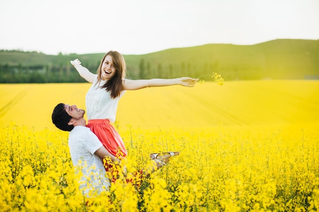 Homem romântico levanta sua namorada desfrutar de união na bela pose de campo amarelo ao ar livre divirta-se sorrir com alegria Casal apaixonado passa férias de verão na natureza Pessoas e conceito de harmonia