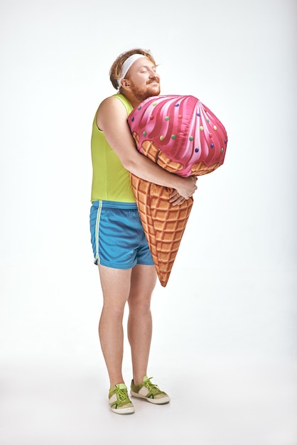 Homem ruivo barbudo e gordo segurando um grande sorvete