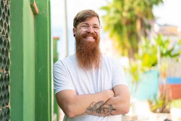 Foto homem ruivo com barba com óculos com expressão feliz