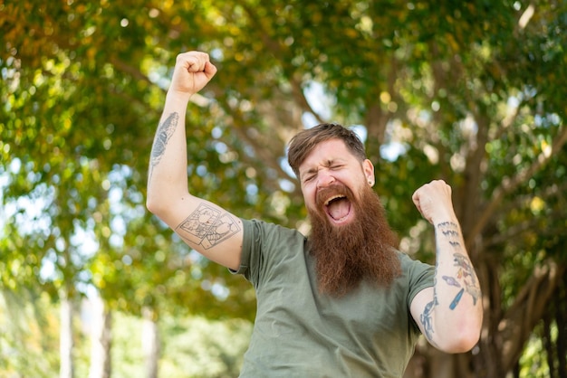 Homem ruivo com barba comemorando uma vitória