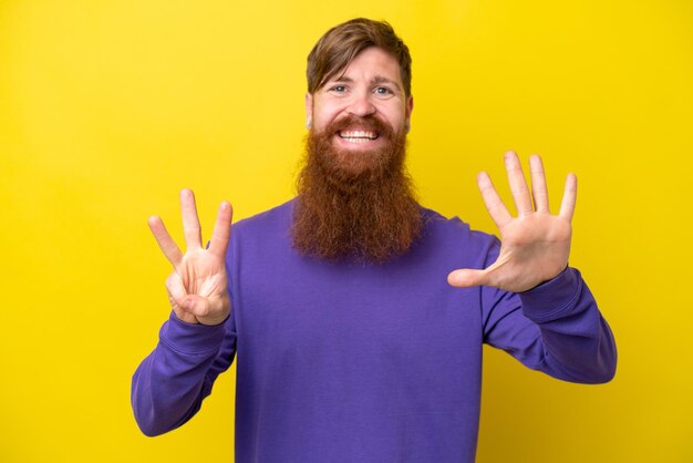 Homem ruivo com barba isolada em fundo amarelo contando oito com os dedos