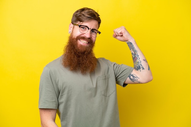 Homem ruivo com barba isolada em fundo amarelo, fazendo um gesto forte