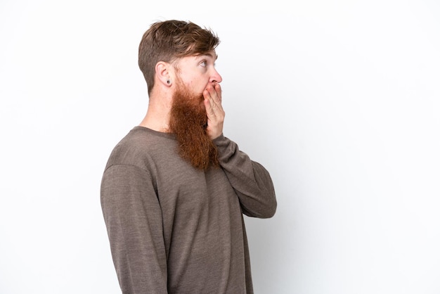 Homem ruivo com barba isolada no fundo branco fazendo gesto de surpresa enquanto olha para o lado