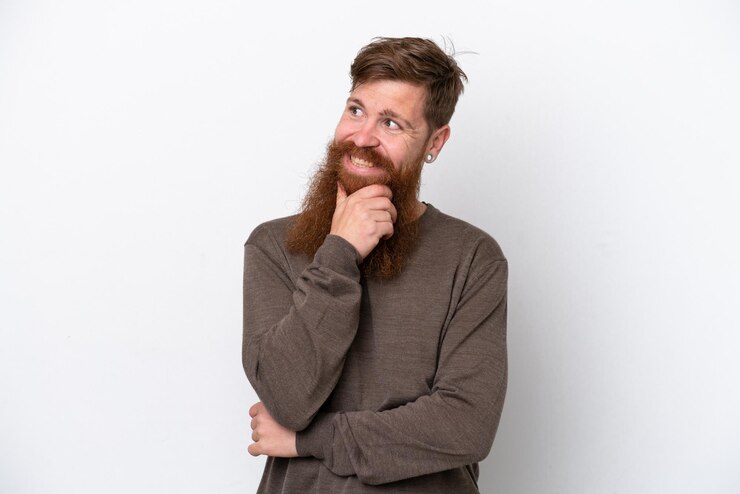 Foto homem ruivo com barba isolada no fundo branco, olhando para o lado e sorrindo