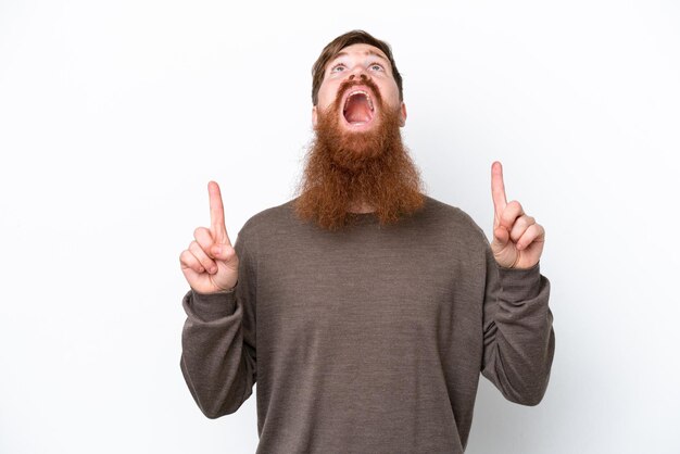 Homem ruivo com barba isolada no fundo branco surpreso e apontando para cima