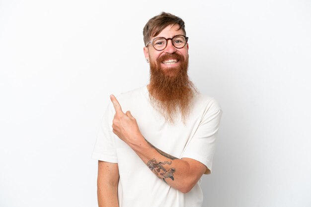 Homem ruivo com barba longa, isolado no fundo branco, apontando para o lado para apresentar um produto