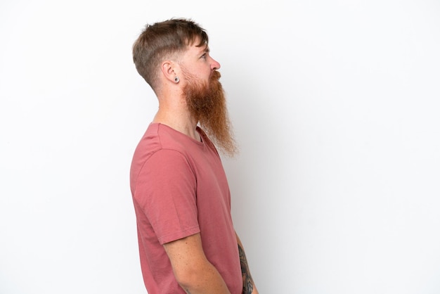 Homem ruivo com barba longa isolado no fundo branco em posição lateral